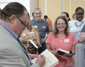 Author and clinical social worker Christian Moore signing books for faculty and staff at the district-wide summer convocation.