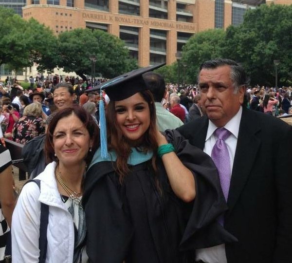 Graduate in cap and gown with parents at commencement