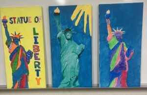 Three student paintings on canvas featuring stylized versions of the Statue of Liberty