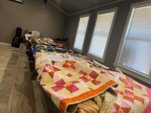 A display of the large number and variety of quilts donated to the boys at Pathways from the Giver Connection.