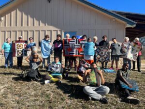 The boys of Pathways and members of the Giver Connection show off the quilts that were donated.