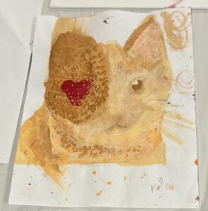 Student watercolor of an orange cat with a red heart as the cat's right eye